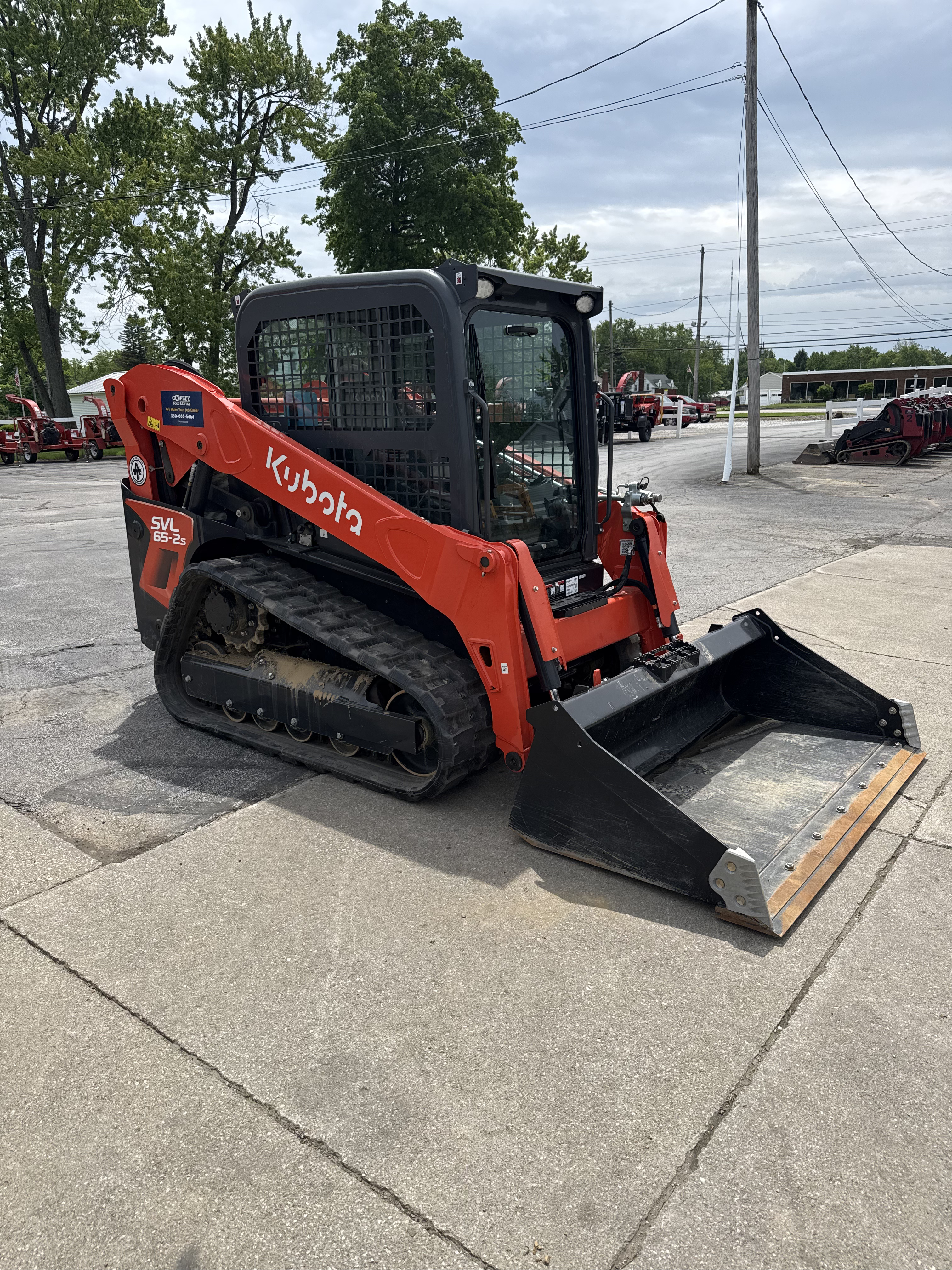 Loader with hydraulic arms that runs on rubber tracks rather than wheels. Has enclosed cab for operator.